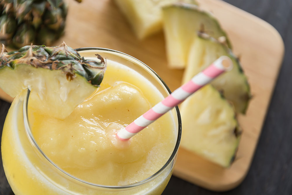 یک لیوان کوکتل انبه و آناناس تهیه شده با ماءالشعیر با تزئین آناناس